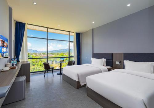 a hotel room with two beds and a desk with a view at Lisha Garden Resort in Vang Vieng