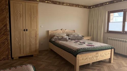 a bedroom with a bed and a cabinet and a window at Apartament u Bafiów in Chochołów