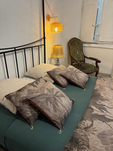 a bed with three pillows on it with a lamp and a chair at Tour XIIIe siècle, vue mer, Cap Corse in Brando