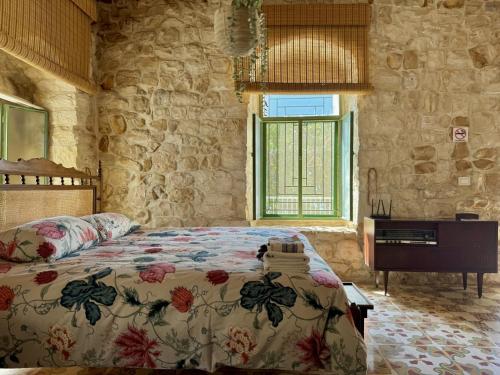 a bedroom with a bed and a desk in a stone wall at Beit El Berbara-Pool & Breakfast in Al Ḩulwah