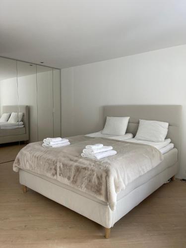 a white bedroom with a large bed with towels on it at Wasserfall - Zentrum - Balkon - Seeblick - Küche in St. Moritz