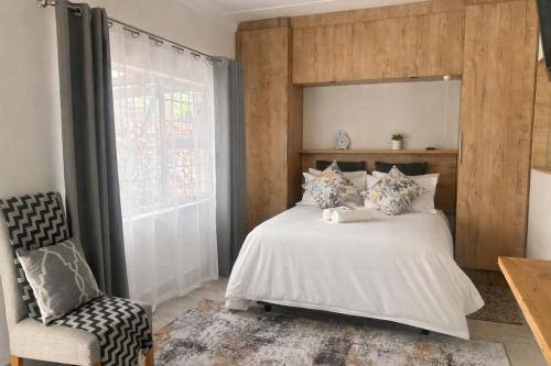 a bedroom with a white bed and a chair at Ameni Air B&B in Gqeberha