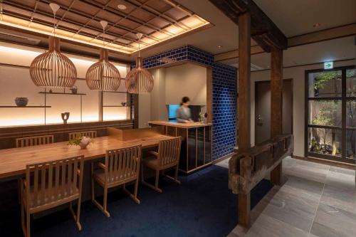 a room with a table and chairs and a woman sitting at a desk at THE MACHIYA KAZAHAYA in Kyoto