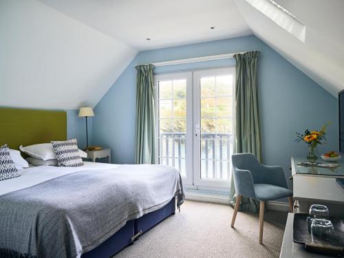 a bedroom with blue walls and a bed and a window at Lugger Hotel ‘A Bespoke Hotel’ in Portloe