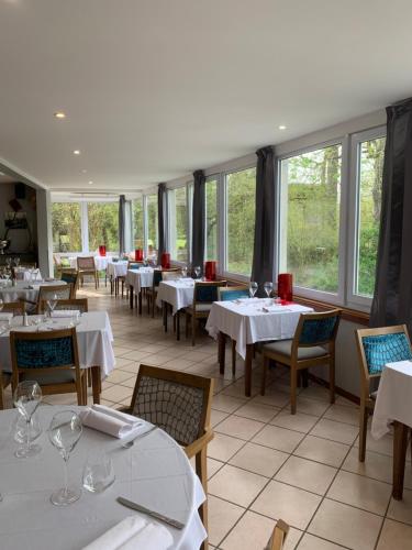 un restaurant avec des tables et des chaises blanches et des fenêtres dans l'établissement Le Clos De Mutigny, à La Chaussée-sur-Marne