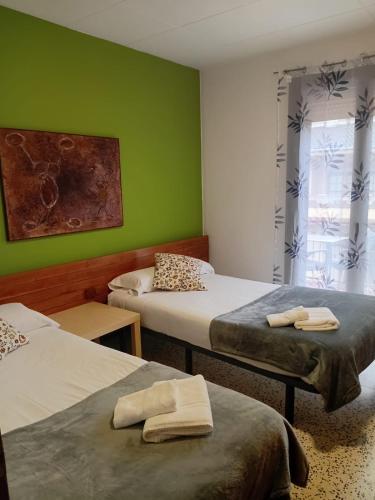 a room with two beds and a green wall at Hostal Collsacabra in L’ Esquirol