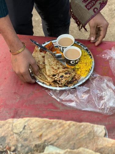 a plate of food on a table with two cups of coffee at Jalpa Camp Kasol in Kulu