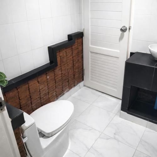 a bathroom with a white toilet and a sink at Earth House HomeStay Bangjo in Ban Pak Lak