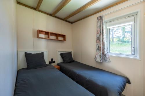 two beds in a small room with a window at Camping Domaine Saâne et Mer in Quiberville