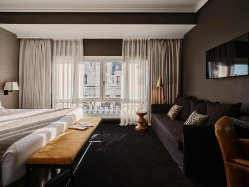 a hotel room with a bed and a couch at The Principal Madrid, Small Luxury Hotels in Madrid