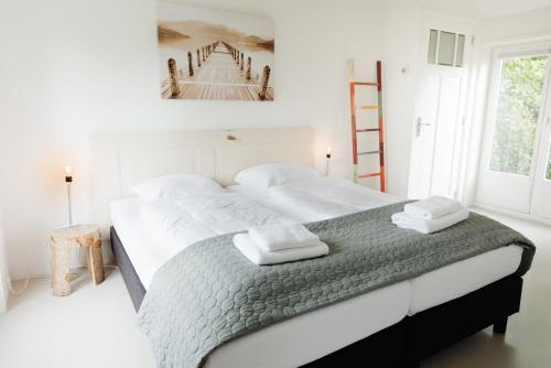 a bedroom with a large bed with towels on it at Simmerwille - stilte accommodaties in nationaal park de Alde Feanen in Earnewâld