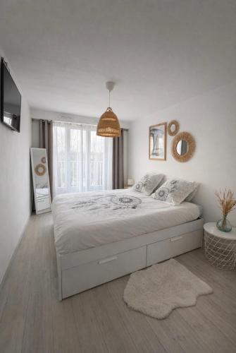 a white bedroom with a bed and a large window at Appartement Chilly Mazarin T3 Proche Aéroport Orly in Chilly-Mazarin