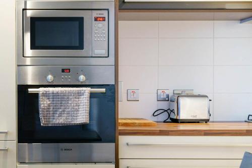 a kitchen with a oven with a microwave above it at Luxury & Central 2 Bedroom Ormeau Road Apartment in Belfast