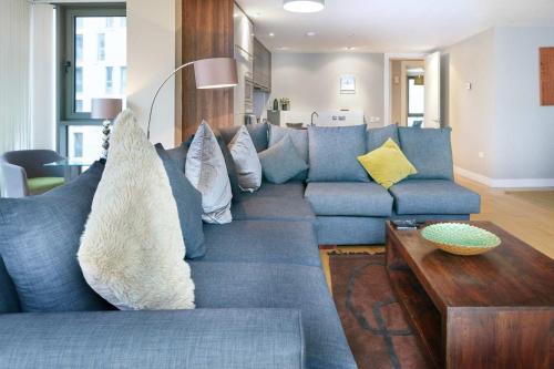 a living room with a blue couch with pillows at Luxury & Central 2 Bedroom Ormeau Road Apartment in Belfast