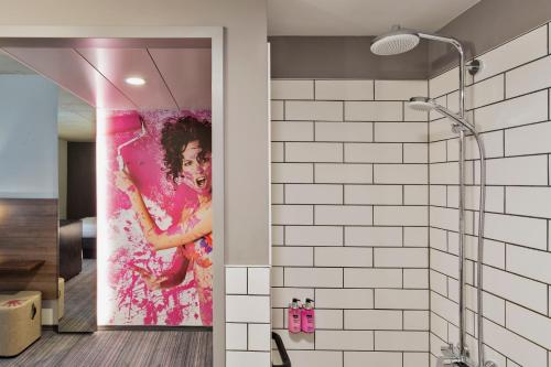 a bathroom with a shower with a painting on the wall at MOXY Frankfurt East in Frankfurt