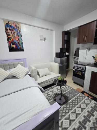 a bedroom with a bed and a couch and a kitchen at ML STUDIO with Rooftop, Free wifi, Free Parking in Nakuru