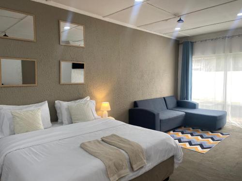 a bedroom with a large bed and a blue chair at Desert Rose Apartments - Lusaka Zambia in Lusaka