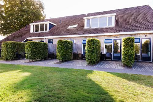 a house with hedges in front of a yard at Simmerwille B&B- Camping- Bootverhuur in Earnewâld