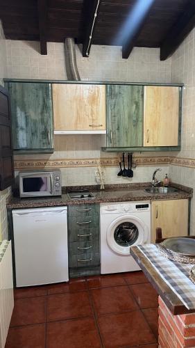a kitchen with a washing machine and a microwave at Casa de Aldea EL ACEBU in Bierces