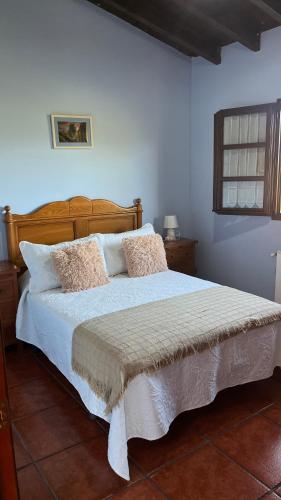 a bedroom with a bed with white sheets and pillows at Casa de Aldea EL ACEBU in Bierces