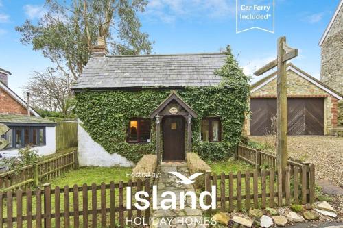 a house covered in ivy with a wooden fence at Lavender Cottage in Arreton