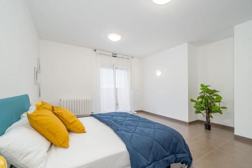 a bed with yellow and blue pillows in a room at Jouvacations Ripolles Figueres-Vilafant in Vilafant