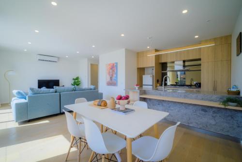 a kitchen and living room with a white table and chairs at Waverley Gardens Modern 3BR Home - Pet Friendly & Parking in Mulgrave