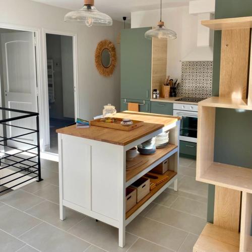 a kitchen with a white island with a wooden counter top at Holiday Home nature and swimming pool in Provence ! in Mérindol