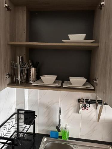 a kitchen with plates and bowls on shelves above a sink at Joto House in Muchatha