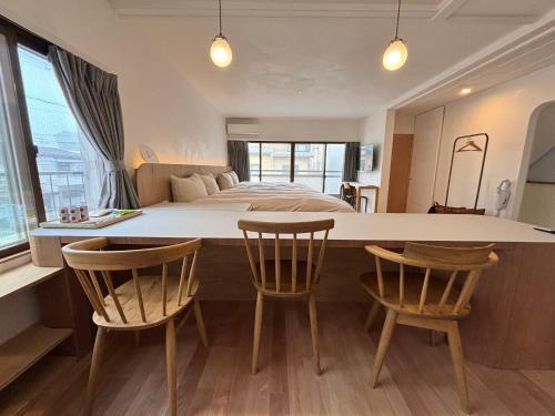 a bedroom with a bed and a table and chairs at ゲストハウス弓と糸 Guesthouse Yumi To Ito 2F in Nagano