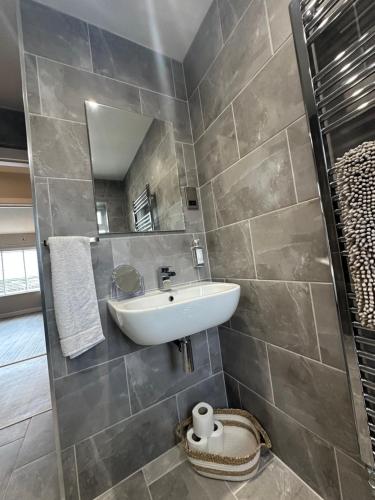 a bathroom with a sink and a mirror at Modern homely well equipped 2BR bungalow next to the racecourse free parking in Hereford