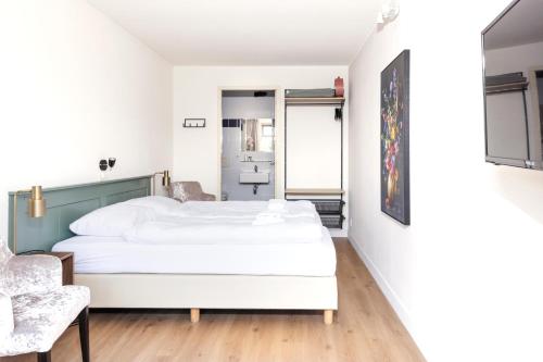 a bedroom with a white bed and a chair at Simmerwille B&B- Camping- Bootverhuur in Earnewâld