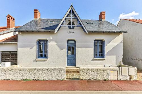 a white house with a blue door at Welcome to Villa Floréal Your tranquil retreat with spa in Saint-Gilles-Croix-de-Vie