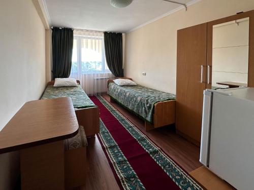 a hotel room with two beds and a refrigerator at Samal Resort and SPA in Taraz