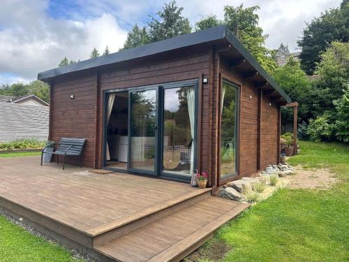 a small cabin with a deck in a yard at Langdale Lodge in Inverness