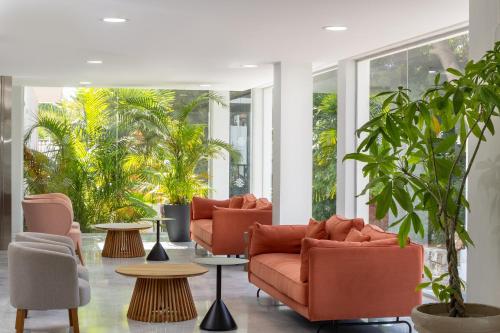 a lobby with orange chairs and tables and plants at AluaSun Costa Park in Torremolinos