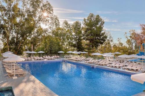 a swimming pool with lounge chairs and umbrellas at AluaSun Costa Park in Torremolinos