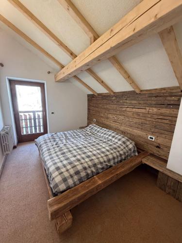a bed in a room with a wooden wall at Baita dal Bigolaro in Vetriola