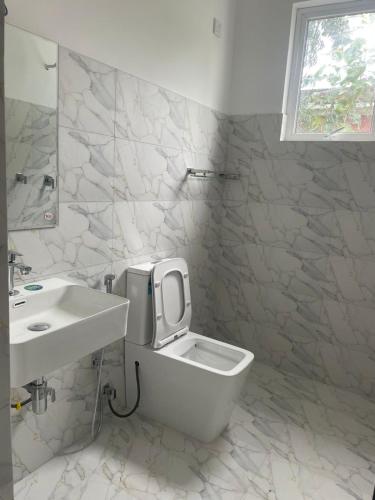 a white bathroom with a toilet and a sink at Anchorage Apartment in Kurunegala