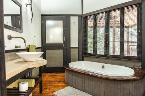 a bathroom with a tub and a sink at Umthiba Bush Lodge in KwaNibela