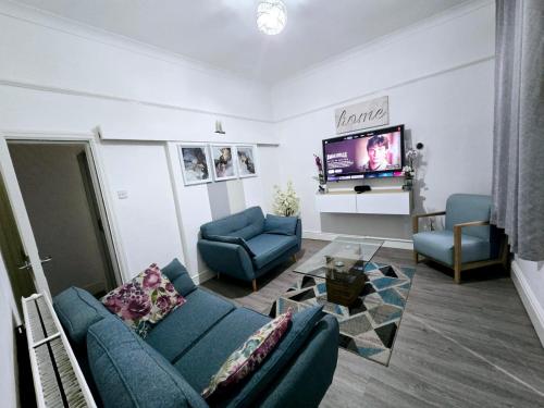 a living room with a blue couch and a tv at Cheerful Home near Preston train station & Uclan in Preston