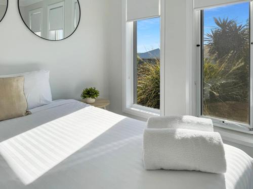 a white bedroom with a large bed and a mirror at Paradise Stay in North Wagga