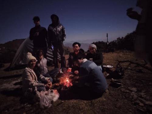 a group of people sitting around a fire at Himalayan Cloud Door Camps in Dehradun