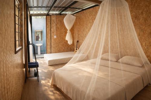 a bedroom with a bed with a mosquito net at แม่ไพโฮมสเตย์ ล่องแพกอนโดล่า in Ban Racha Tai