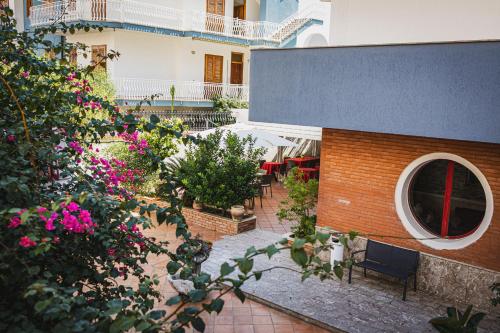an outdoor patio with pink flowers and a building at Hotel Alexander in Giardini Naxos
