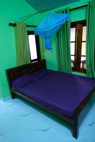 a bedroom with a bed with purple sheets and a window at MENAKA HOMESTAY in Tangalle