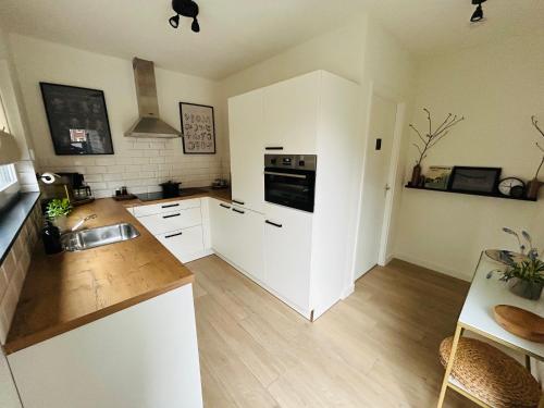 a kitchen with white cabinets and a stove top oven at Ons huisje in Schoot