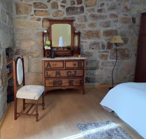 a bedroom with a dresser and a mirror in a stone wall at Cantinho do Ribeiro in Lourosa da Trapa