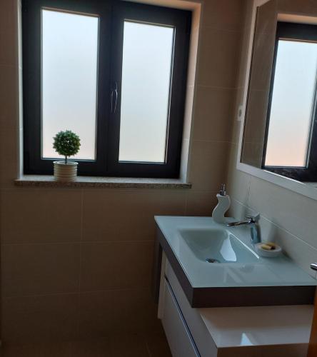 a bathroom with a sink and two windows at Cantinho do Ribeiro in Lourosa da Trapa