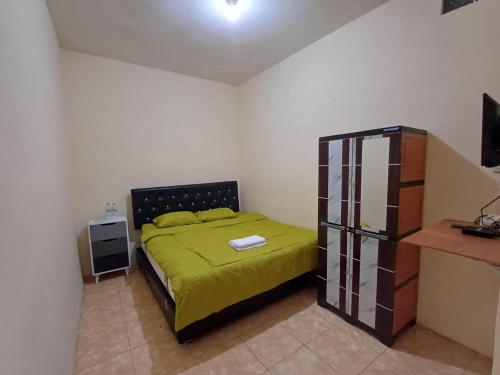 a bedroom with a bed with a green bedspread at Irma Guest House Syariah in Temenggungan